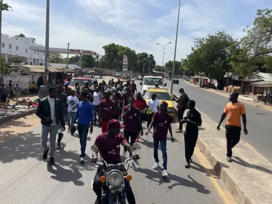 Young people marching together in a street outreach, The Gambia, 2022
